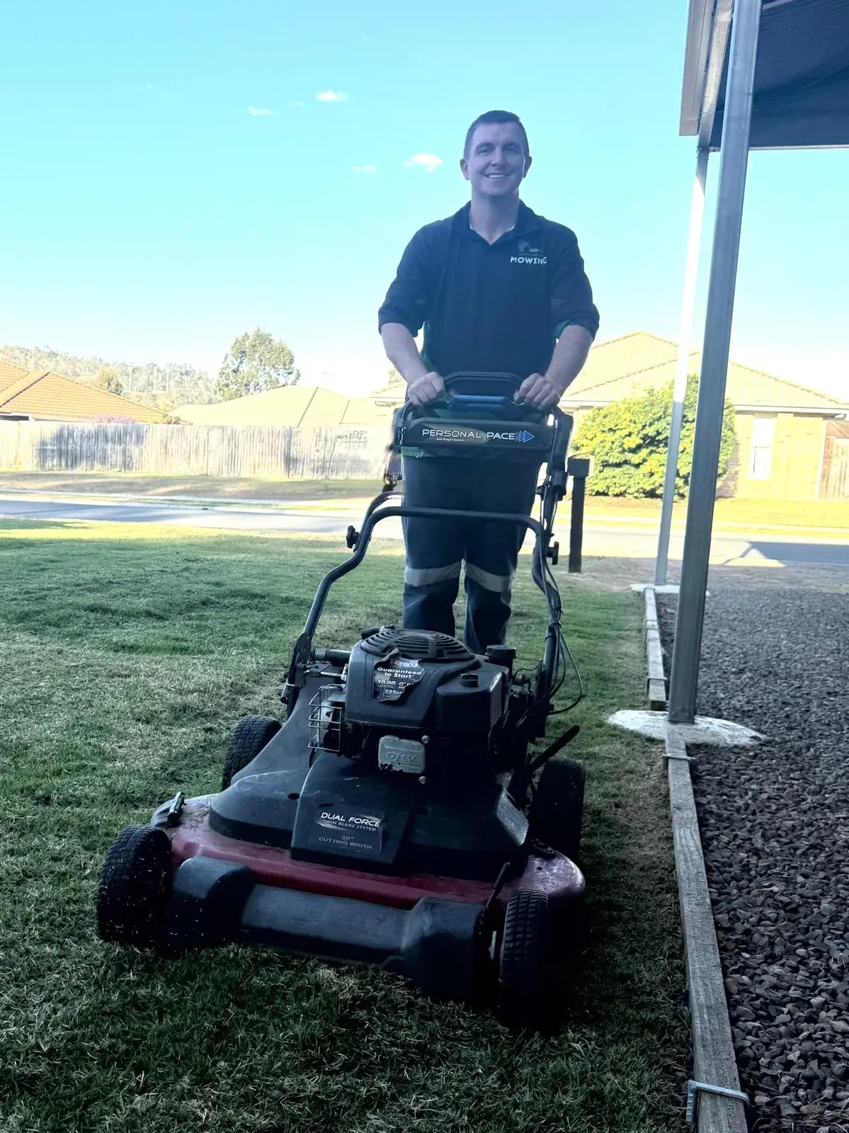 Johnross behind a wide-deck mower on a Fernvale front lawn